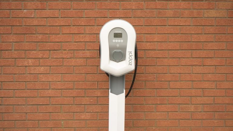 A residential EV charging station with a brick wall in the background.