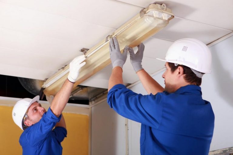 Two commercial electricians repairing office lighting