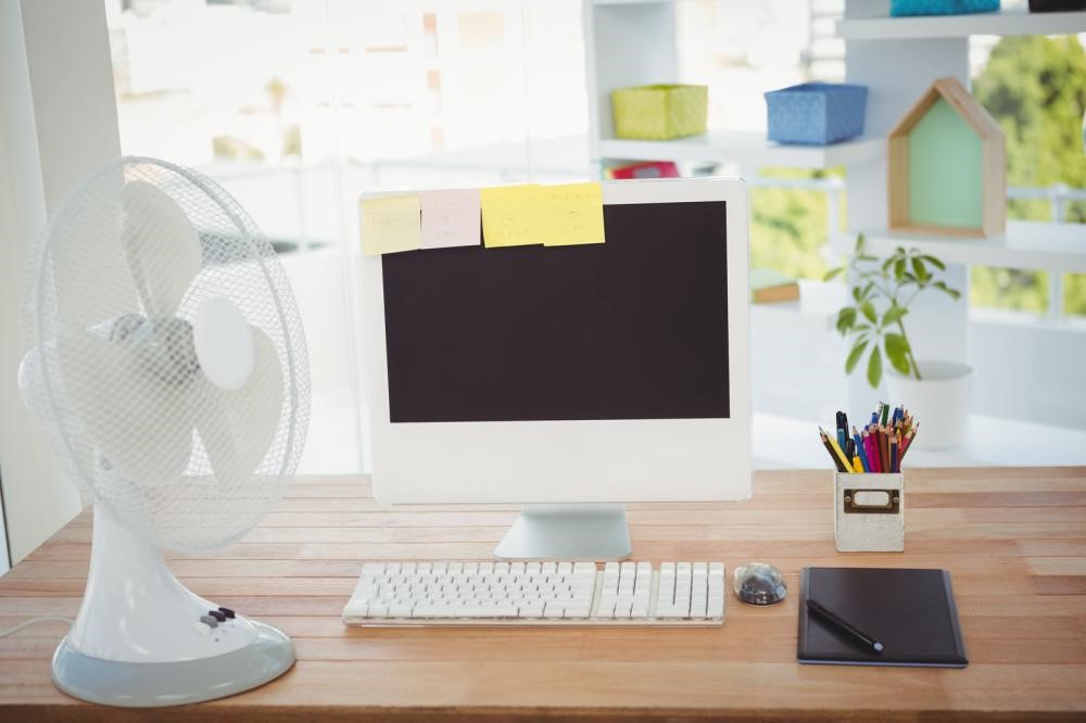 Sticky notes on a closed computer monitor by an electric fan at a desk in office during a power outage.