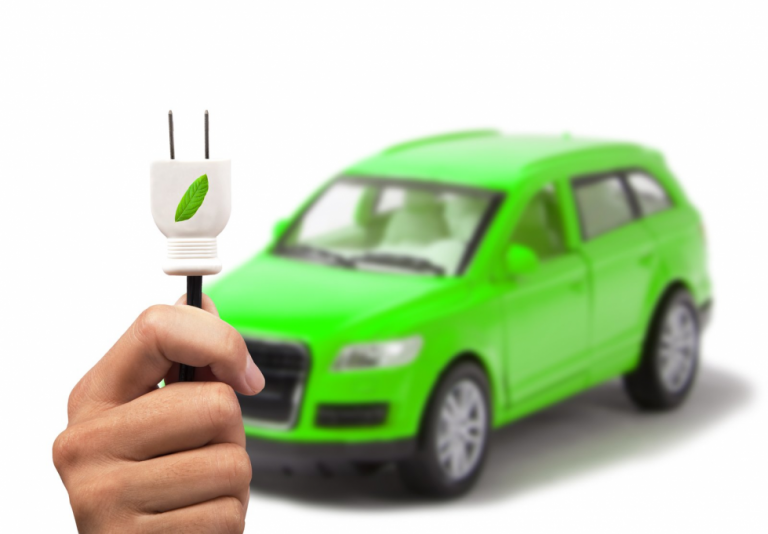 Green electric car with a plug in the foreground indicating fast and eco-friendly charging